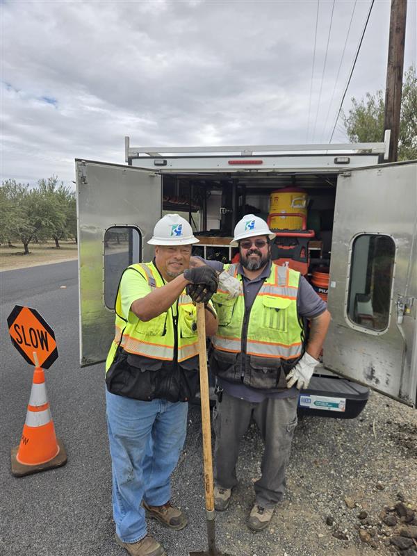 Two workers standing in front of their truck smiling